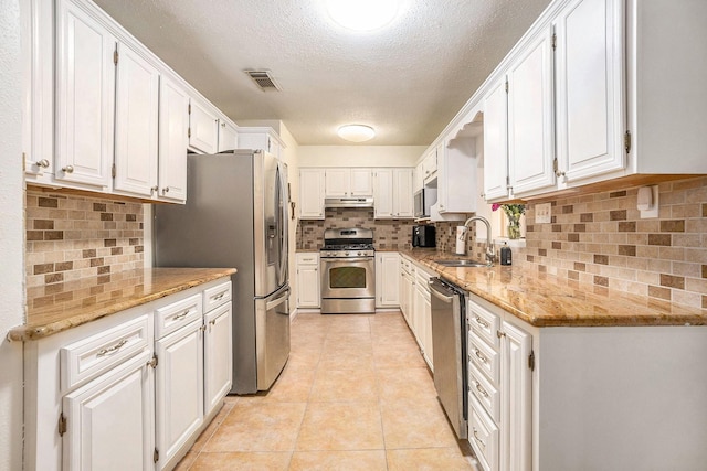 116 Whiting St, Galveston, TX 77550 - kitchen with stainless steel appliances, a sink, under cabinet range hood, white cabinetry, and a textured ceiling