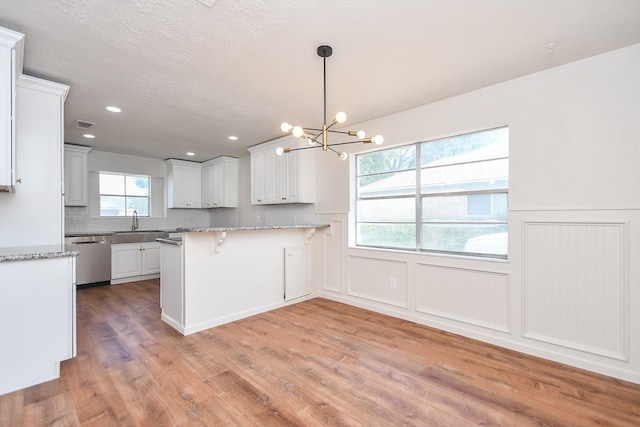 4618 Turf Valley Dr, Houston, TX 77084 - kitchen with dishwasher, a chandelier, light wood-type flooring, a breakfast bar area, and a peninsula
