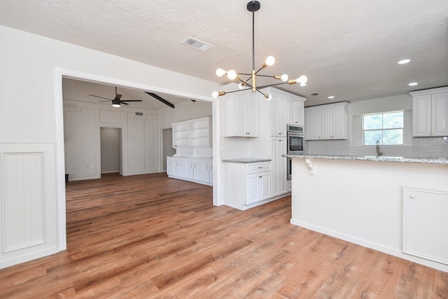 4618 Turf Valley Dr, Houston, TX 77084 - kitchen with a chandelier, light wood-type flooring, a ceiling fan, white cabinets, and a textured ceiling