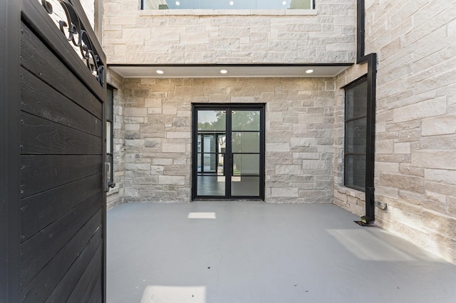 10070 Cedardale Dr, Houston, TX 77055 - view of exterior entry featuring stone siding, french doors, and a patio