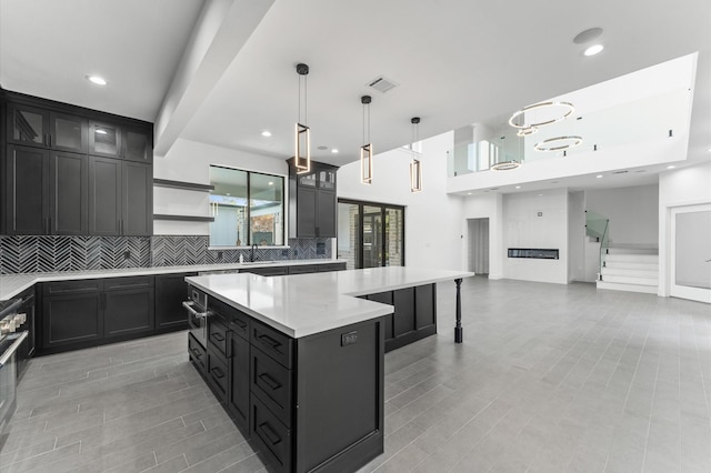 10070 Cedardale Dr, Houston, TX 77055 - kitchen featuring decorative backsplash, light countertops, a sink, dark cabinetry, and a kitchen island