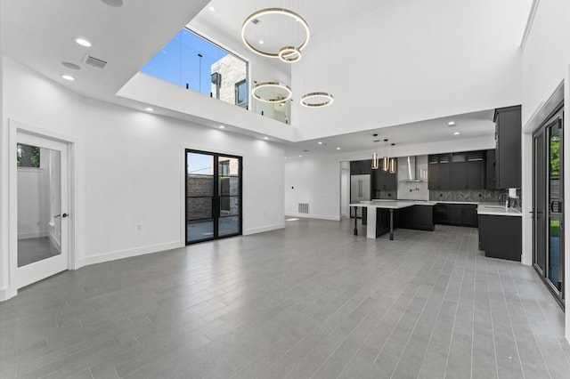 10070 Cedardale Dr, Houston, TX 77055 - unfurnished living room featuring a towering ceiling, a sink, healthy amount of natural light, light wood finished floors, and baseboards