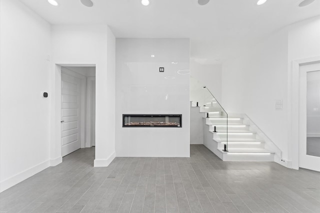 10070 Cedardale Dr, Houston, TX 77055 - unfurnished living room with a glass covered fireplace, recessed lighting, stairway, wood finished floors, and baseboards