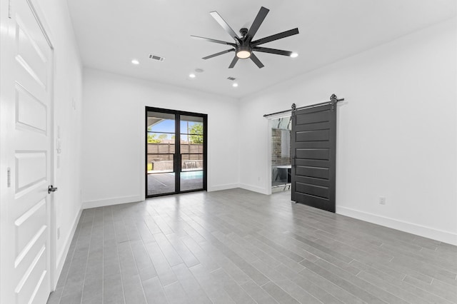 10070 Cedardale Dr, Houston, TX 77055 - unfurnished room featuring a barn door, baseboards, ceiling fan, wood finished floors, and recessed lighting