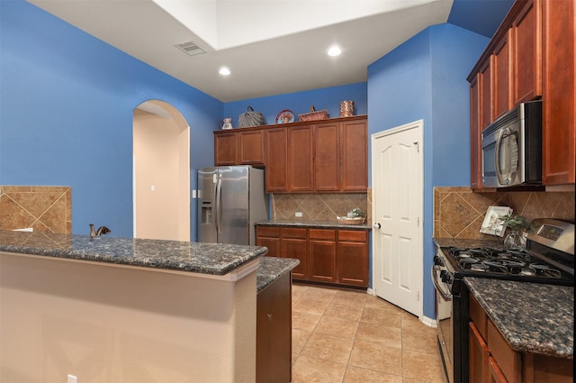 1027 Nantucket St, Pasadena, TX 77503 - kitchen with appliances with stainless steel finishes, arched walkways, decorative backsplash, dark stone counters, and a peninsula