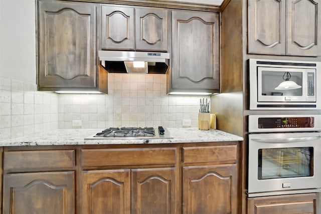 20688 Oakhurst Meadows Dr, Porter, TX 77365 - kitchen with stainless steel appliances, under cabinet range hood, decorative backsplash, and light stone countertops