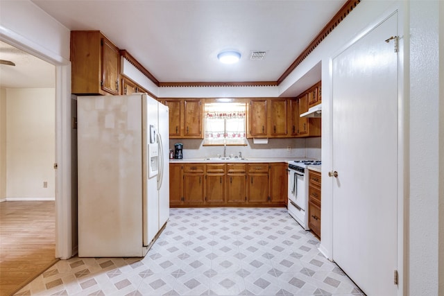 119 Delaware Dr, Conroe, TX 77316 - kitchen with white appliances, a sink, brown cabinetry, light countertops, and under cabinet range hood