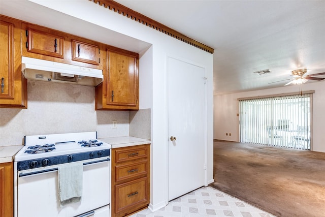 119 Delaware Dr, Conroe, TX 77316 - kitchen with gas range gas stove, under cabinet range hood, brown cabinets, light countertops, and ceiling fan