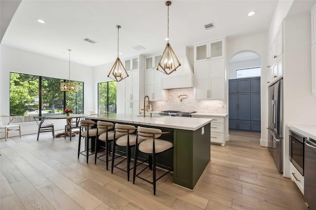 1913 Ebony Ln, Houston, TX 77018 - kitchen featuring decorative backsplash, a kitchen island with sink, recessed lighting, glass insert cabinets, and white cabinets