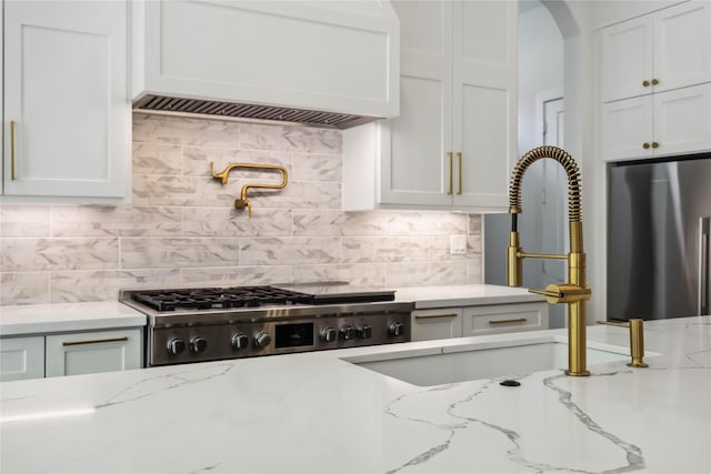 1913 Ebony Ln, Houston, TX 77018 - kitchen with stainless steel appliances, premium range hood, white cabinetry, tasteful backsplash, and arched walkways