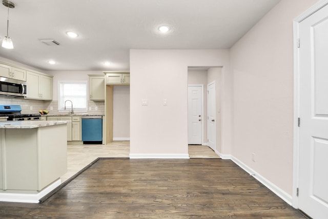 4918 Perry St, Houston, TX 77021 - kitchen featuring appliances with stainless steel finishes, a sink, decorative backsplash, wood finished floors, and baseboards