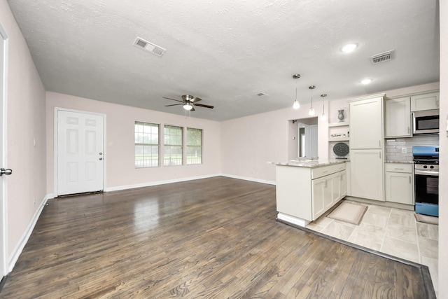4918 Perry St, Houston, TX 77021 - kitchen with stainless steel appliances, a peninsula, a ceiling fan, wood finished floors, and baseboards