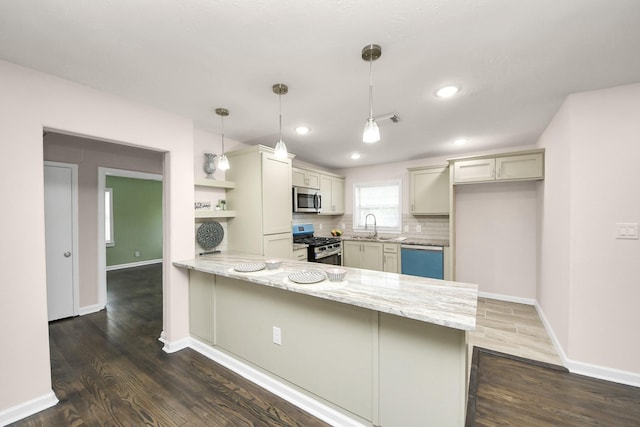 4918 Perry St, Houston, TX 77021 - kitchen featuring stainless steel appliances, a peninsula, dark wood-style floors, light stone countertops, and recessed lighting