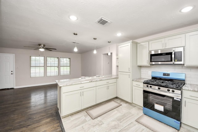 4918 Perry St, Houston, TX 77021 - kitchen with appliances with stainless steel finishes, a peninsula, light stone countertops, a ceiling fan, and recessed lighting