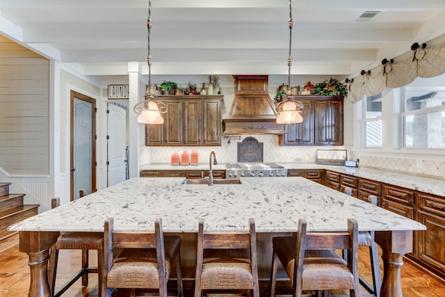 321 Marina Dr, Coldspring, TX 77331 - kitchen featuring decorative backsplash, beam ceiling, a sink, custom exhaust hood, and light stone counters