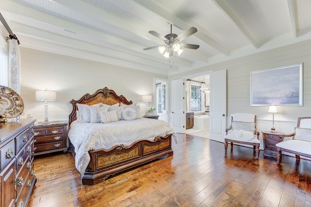 321 Marina Dr, Coldspring, TX 77331 - bedroom with wood-type flooring, beamed ceiling, wooden walls, connected bathroom, and a ceiling fan