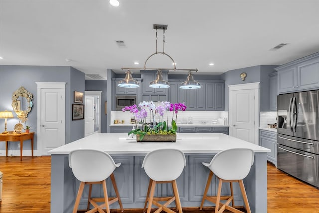 1819 Mill Creek Dr, Houston, TX 77008 - kitchen featuring appliances with stainless steel finishes, gray cabinetry, backsplash, light countertops, and a spacious island