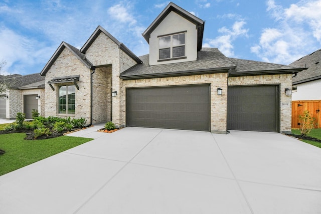 21111 Flowerhorn Dr, Cypress, TX 77433 - french country style house featuring concrete driveway, a shingled roof, brick siding, and a garage