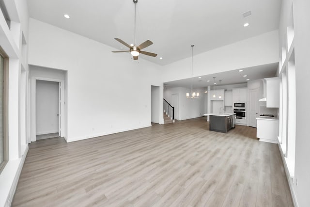 21111 Flowerhorn Dr, Cypress, TX 77433 - unfurnished living room featuring a towering ceiling, recessed lighting, stairs, light wood-type flooring, and ceiling fan