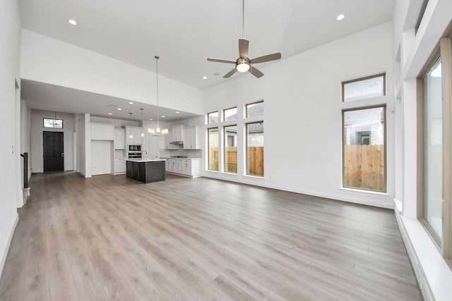 21111 Flowerhorn Dr, Cypress, TX 77433 - unfurnished living room featuring a towering ceiling, ceiling fan, light wood-type flooring, and recessed lighting