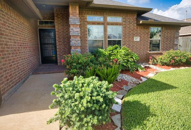 107 Brazos Ct, Richwood, TX 77531 - property entrance featuring brick siding, a shingled roof, and a lawn