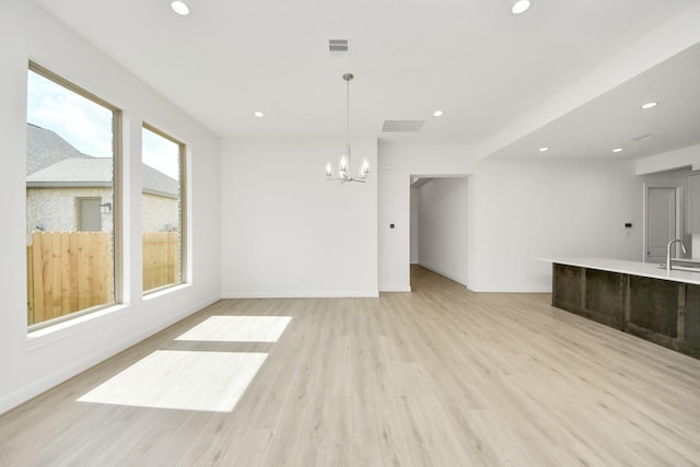 21122 Flowerhorn Dr, Cypress, TX 77433 - unfurnished living room with recessed lighting, a chandelier, light wood-style flooring, a sink, and baseboards