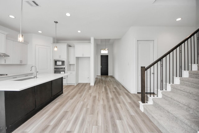 21114 Regal Terrace Dr, Cypress, TX 77433 - kitchen featuring stainless steel appliances, a sink, white cabinets, light countertops, and light wood finished floors