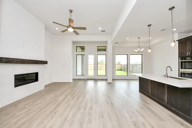 21130 Flowerhorn Dr, Cypress, TX 77433 - unfurnished living room featuring a glass covered fireplace, light wood-type flooring, a ceiling fan, a sink, and a chandelier