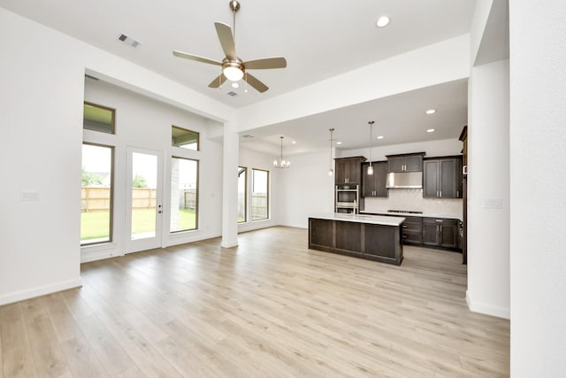 21130 Flowerhorn Dr, Cypress, TX 77433 - kitchen featuring open floor plan, dark brown cabinets, light countertops, a center island with sink, and ceiling fan