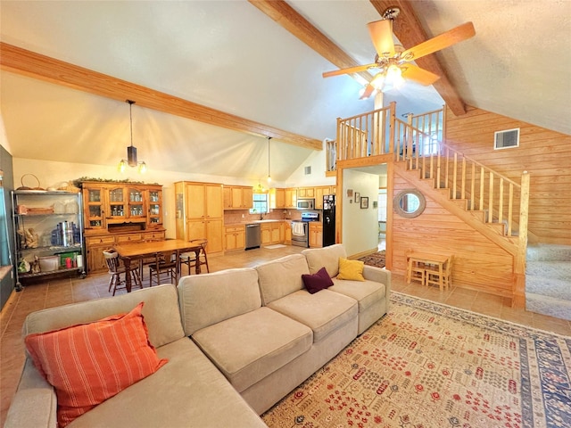 798 Port Blvd, Trinity, TX 75862 - living area featuring wood walls, beamed ceiling, stairway, a ceiling fan, and high vaulted ceiling
