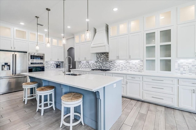 8105 Denali Dr, Corpus Christi, TX 78414 - kitchen with stainless steel appliances, premium range hood, a sink, white cabinetry, and a kitchen island with sink