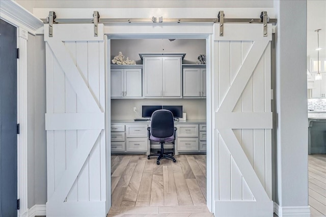 8105 Denali Dr, Corpus Christi, TX 78414 - home office with a barn door, built in study area, and light wood-type flooring