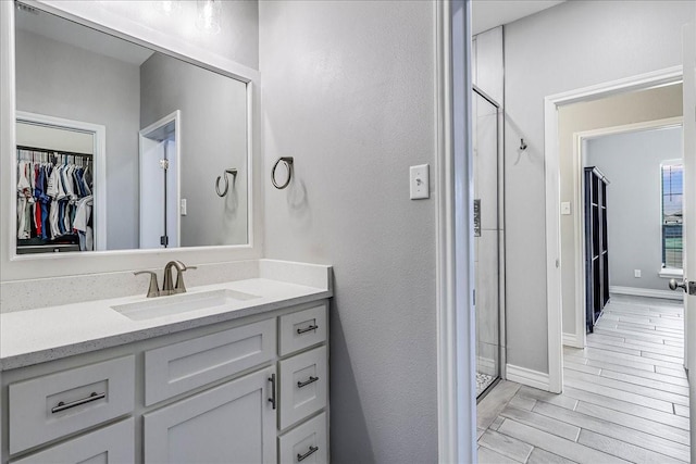 8105 Denali Dr, Corpus Christi, TX 78414 - bathroom featuring vanity, a shower stall, a spacious closet, wood finished floors, and baseboards