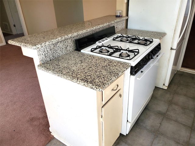 4919 Redfish Reef St, Bacliff, TX 77518 - kitchen featuring white gas range oven, light stone countertops, and dark carpet