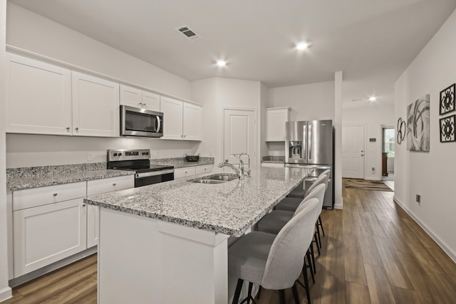 3511 Queensberry Ct, Huffman, TX 77336 - kitchen featuring appliances with stainless steel finishes, a sink, white cabinets, a kitchen island with sink, and a breakfast bar area