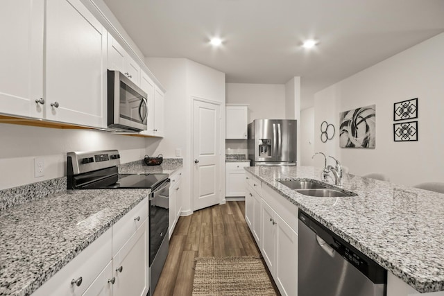 3511 Queensberry Ct, Huffman, TX 77336 - kitchen featuring stainless steel appliances, a sink, dark wood-style flooring, white cabinets, and a kitchen island with sink