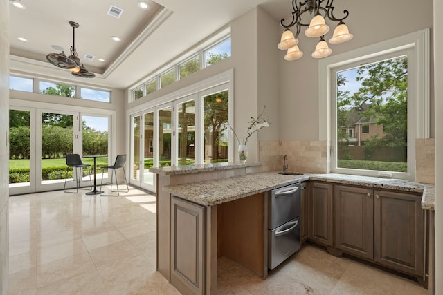 16 Grand Mnr, Sugar Land, TX 77479 - kitchen featuring plenty of natural light, backsplash, a chandelier, light stone counters, and a high ceiling