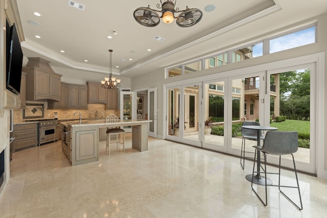 16 Grand Mnr, Sugar Land, TX 77479 - kitchen featuring a chandelier, high end stainless steel range oven, a raised ceiling, tasteful backsplash, and a kitchen breakfast bar