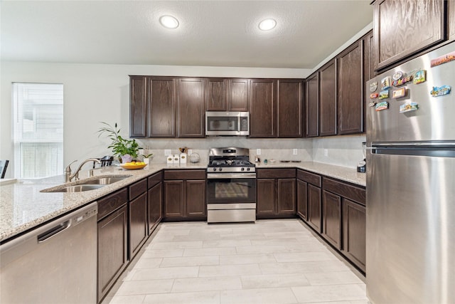 922 Steel Blue Dr, Houston, TX 77073 - kitchen with stainless steel appliances, a sink, dark brown cabinetry, light stone counters, and recessed lighting