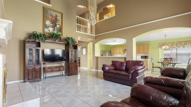 12422 Glenleigh Dr, Houston, TX 77014 - living room with a high ceiling, baseboards, a chandelier, light marble finish flooring, and arched walkways