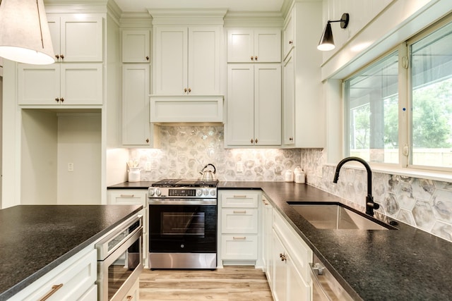 5206 4th St, Danbury, TX 77534 - kitchen with appliances with stainless steel finishes, a sink, light wood-type flooring, and dark stone counters