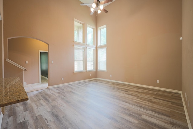 6707 Hunters Creek Ln, Baytown, TX 77521 - empty room with a towering ceiling, ceiling fan, arched walkways, light wood-type flooring, and baseboards
