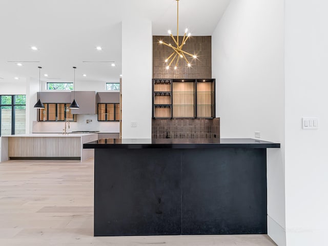 2037 Norfolk St, Houston, TX 77098 - kitchen featuring modern cabinets, a chandelier, a sink, hanging light fixtures, and backsplash