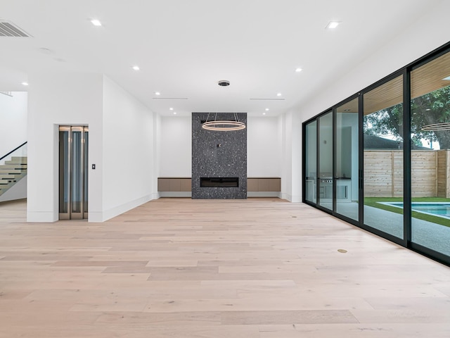 2037 Norfolk St, Houston, TX 77098 - unfurnished living room featuring elevator, light wood finished floors, baseboards, a fireplace, and recessed lighting