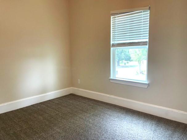 9310 Coffee St, Houston, TX 77033 - spare room with dark colored carpet, baseboards, and healthy amount of natural light