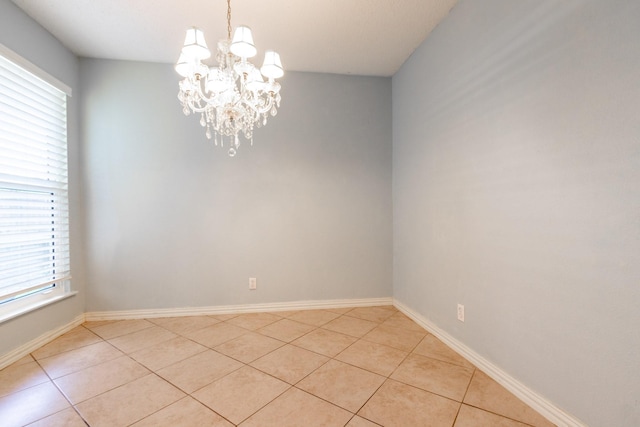 1726 Broadway Unit 19, Galveston, TX 77550 - spare room with a chandelier, healthy amount of natural light, light tile patterned floors, and baseboards