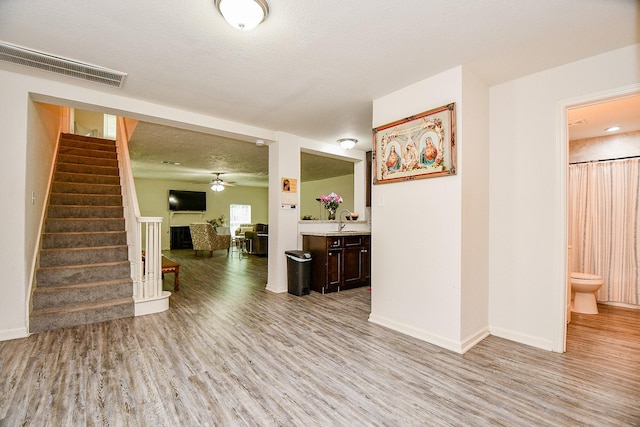 15115 Monrad Dr, Houston, TX 77053 - unfurnished living room featuring light wood finished floors, stairs, a sink, a fireplace, and a textured ceiling