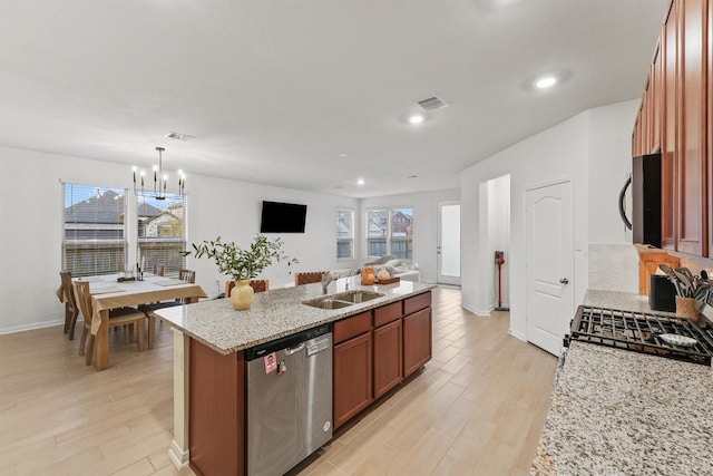7003 Tehama Ln, Rosharon, TX 77583 - kitchen featuring stainless steel dishwasher, a sink, range with gas stovetop, black microwave, and light wood finished floors