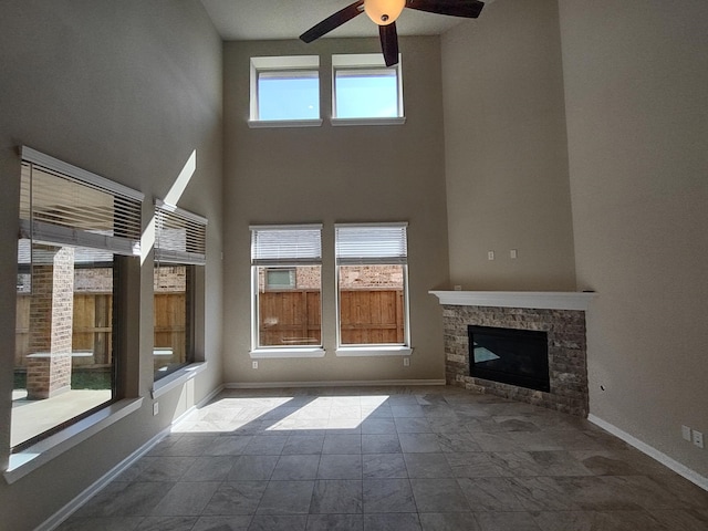 7814 Charter Hill Dr, Magnolia, TX 77354 - unfurnished living room with a ceiling fan, a high ceiling, a stone fireplace, and baseboards