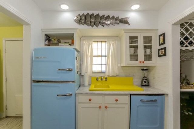 1523 22nd St, Galveston, TX 77550 - kitchen with freestanding refrigerator, glass insert cabinets, backsplash, and white cabinetry